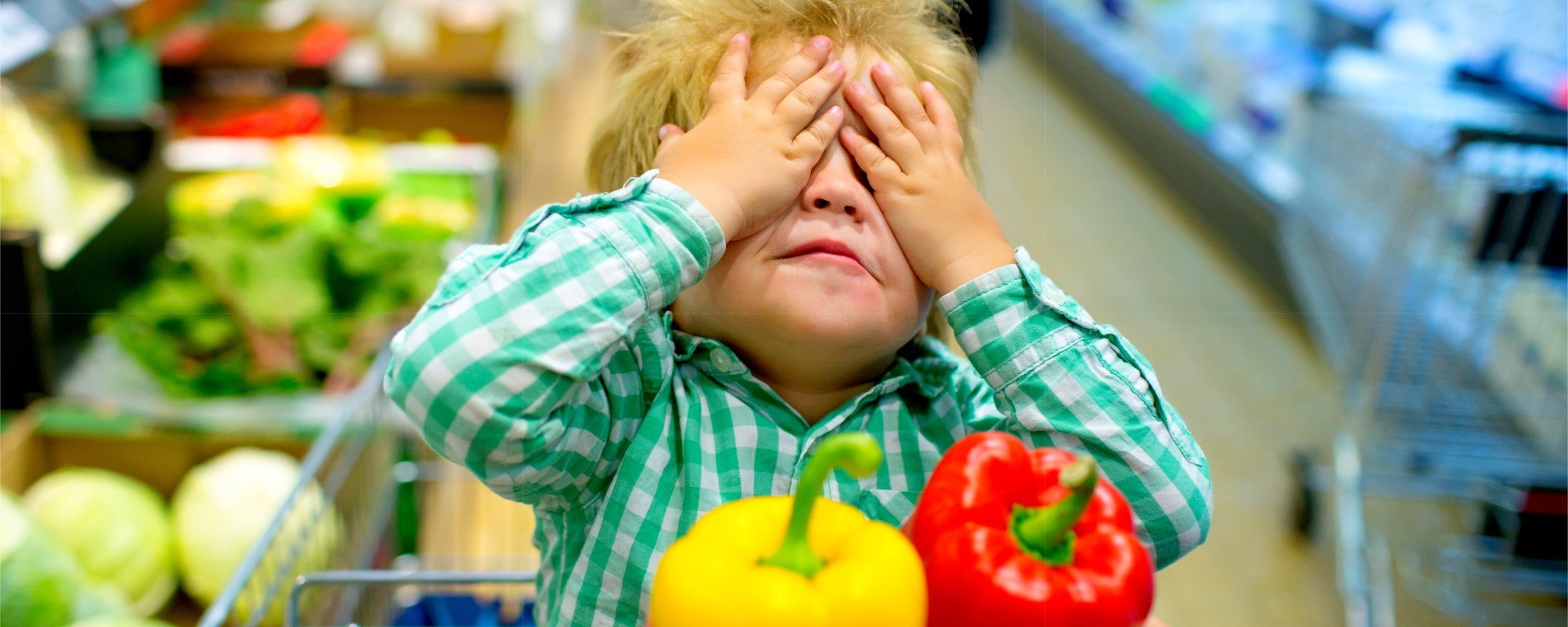 Child covering its face whilst someone holds red and yellow peppers