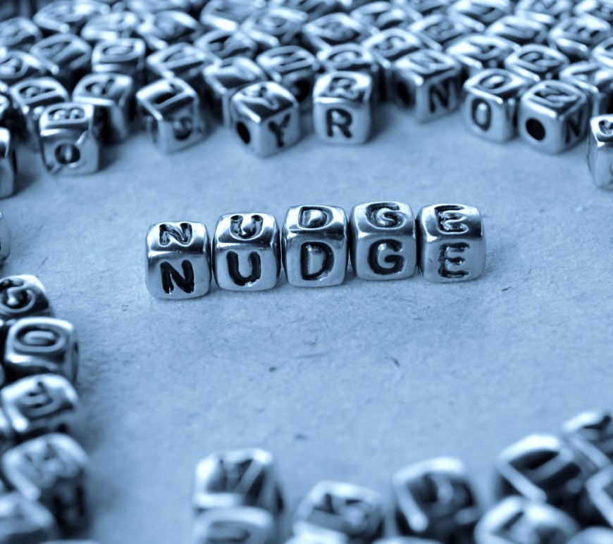 Nudge spelled out from dice with letters on
