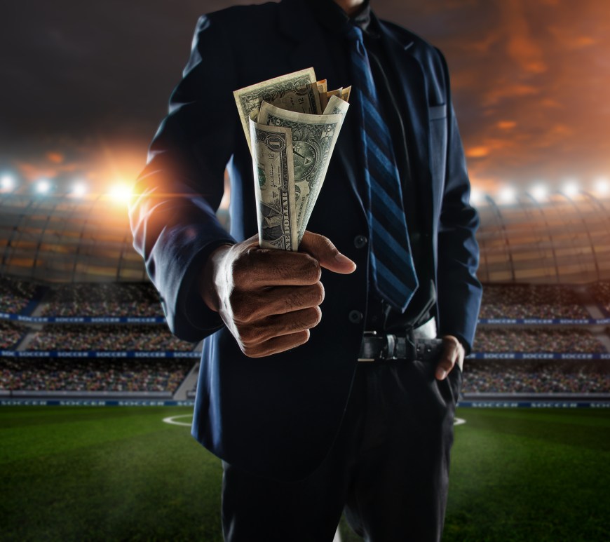 Man in suit holding bank notes in a stadium
